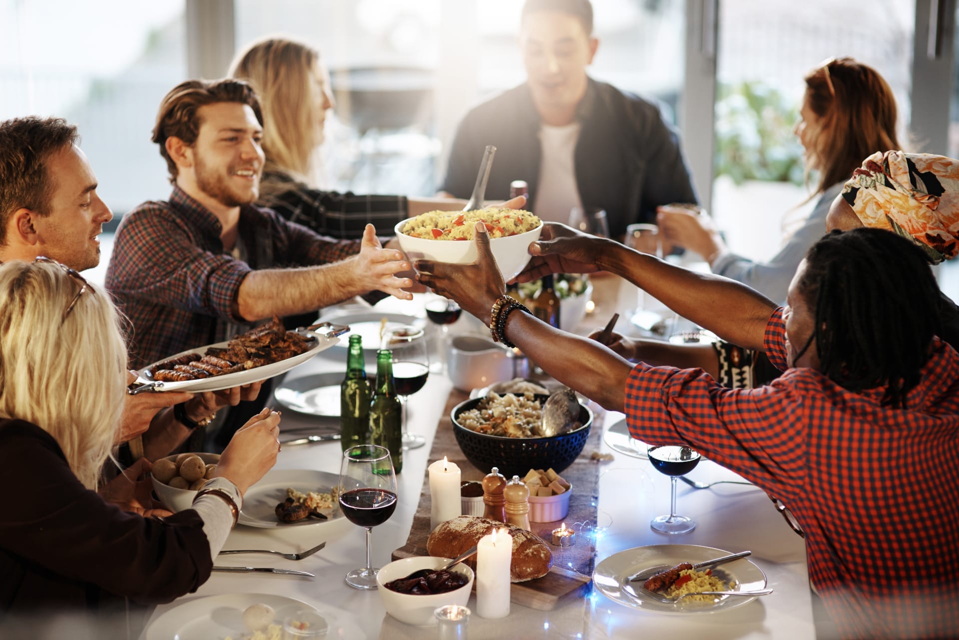 Eine Gruppe von Menschen unterhält sich bei einem gemeinsamen Essen am Tisch. Gemeindeleben gemeinsam genießen.